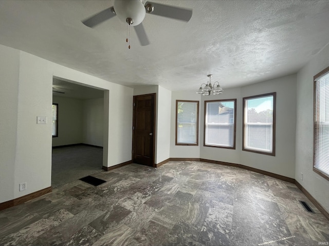 empty room with ceiling fan with notable chandelier and a textured ceiling