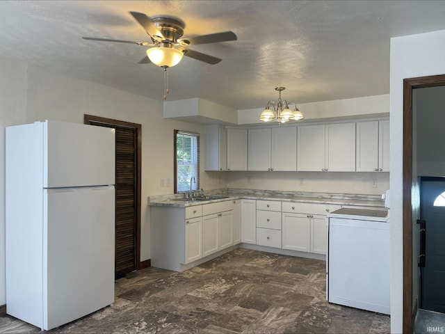 kitchen featuring white cabinets, white refrigerator, ceiling fan with notable chandelier, pendant lighting, and sink