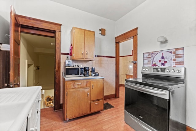 kitchen with light hardwood / wood-style flooring, tile walls, and appliances with stainless steel finishes