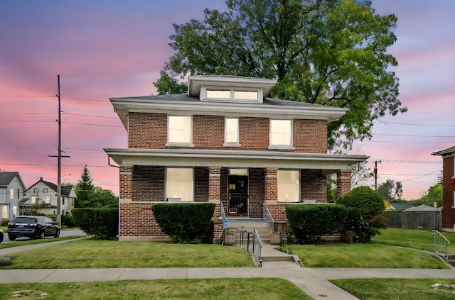 view of front of home with a porch and a lawn