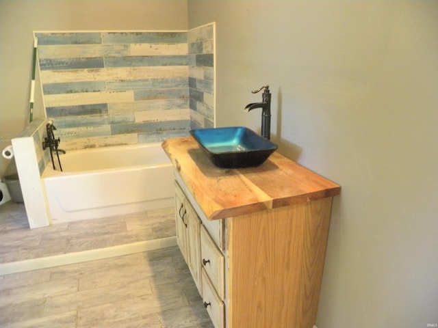 bathroom with wood-type flooring, a bath, and vanity