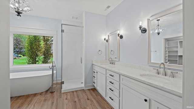 bathroom with a notable chandelier, independent shower and bath, hardwood / wood-style flooring, and vanity