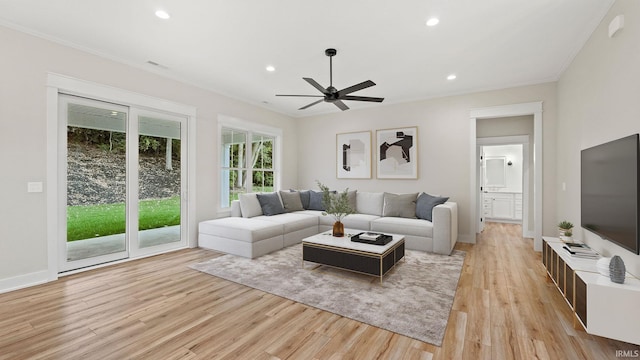 living room with ornamental molding, light wood-type flooring, and ceiling fan