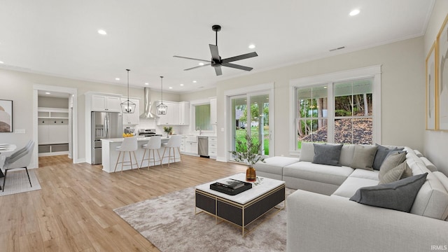 living room with ornamental molding, light wood-type flooring, and ceiling fan