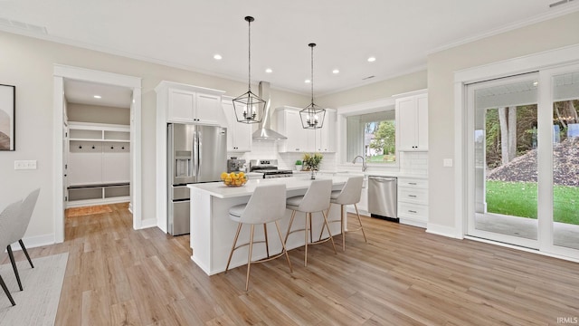 kitchen featuring white cabinets, light hardwood / wood-style flooring, backsplash, wall chimney range hood, and stainless steel appliances