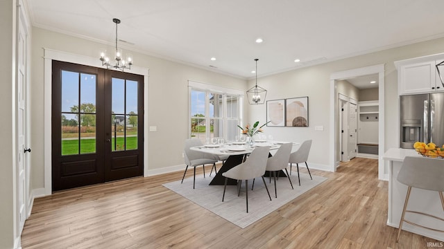 dining area with crown molding, light hardwood / wood-style floors, french doors, and a notable chandelier