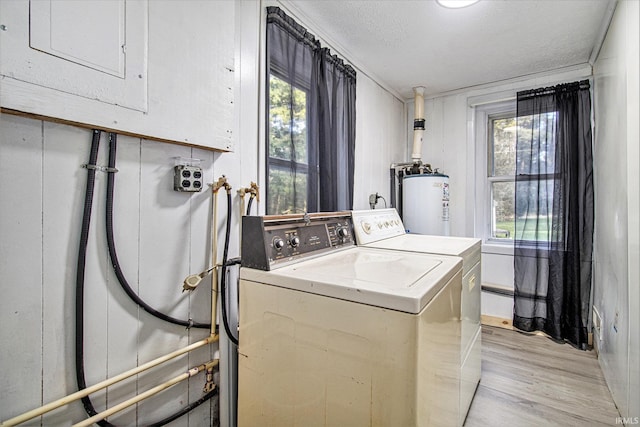 washroom with light hardwood / wood-style floors, electric panel, a textured ceiling, washing machine and clothes dryer, and water heater