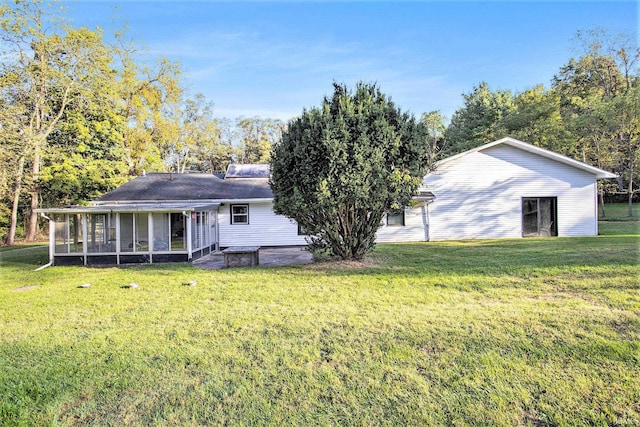 rear view of property with an outbuilding, a lawn, and a sunroom