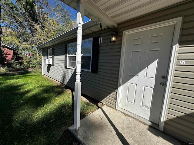 entrance to property featuring a yard and cooling unit