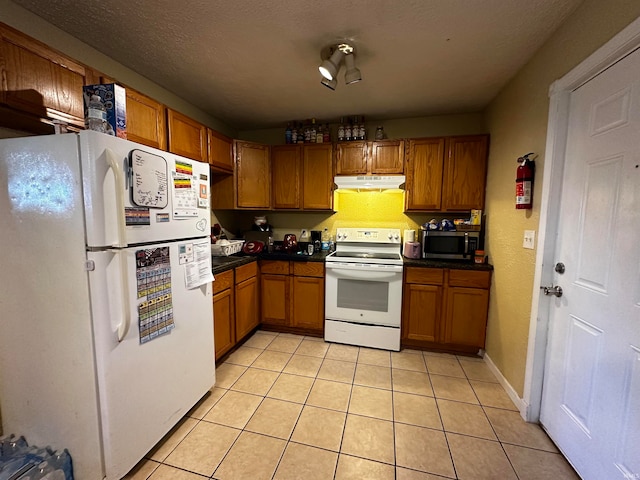 kitchen with a textured ceiling, light tile patterned floors, and white appliances