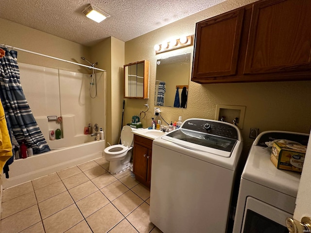 laundry area featuring a textured ceiling, washing machine and dryer, and light tile patterned floors