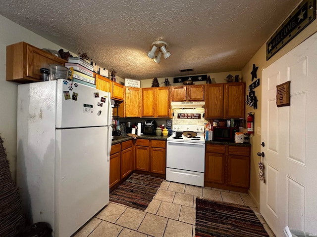 kitchen with white appliances, a textured ceiling, and light tile patterned floors