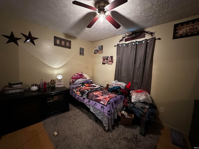 bedroom featuring ceiling fan, hardwood / wood-style floors, and a textured ceiling