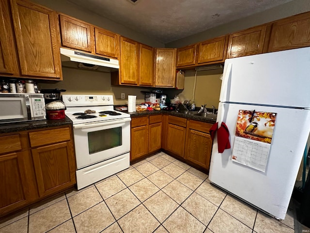 kitchen with light tile patterned floors, white appliances, and a textured ceiling