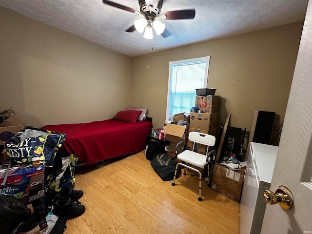 bedroom featuring ceiling fan, wood-type flooring, and a textured ceiling