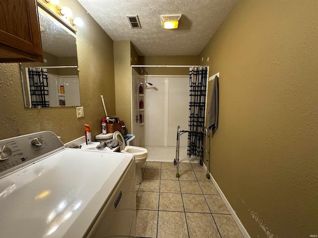 clothes washing area with light tile patterned floors, a textured ceiling, and washer / dryer