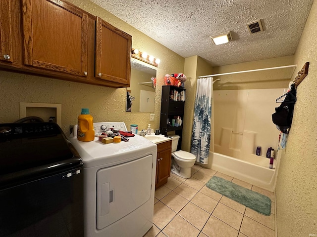 clothes washing area featuring sink, light tile patterned flooring, washer and dryer, and a textured ceiling