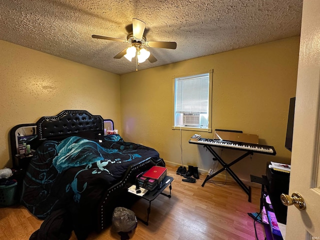 bedroom with ceiling fan, cooling unit, wood-type flooring, and a textured ceiling