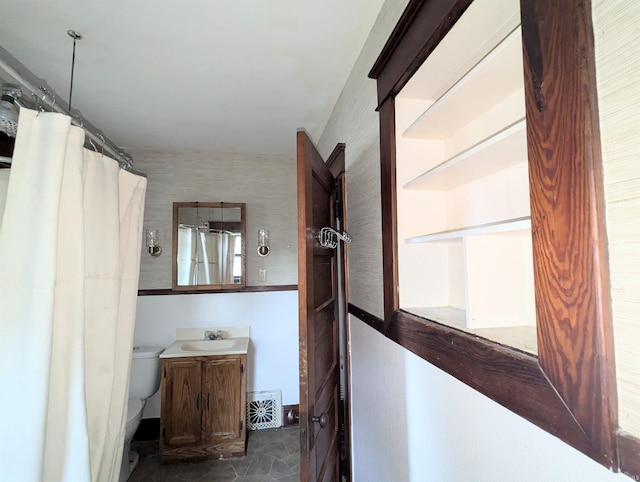 bathroom with walk in shower, vanity, and toilet