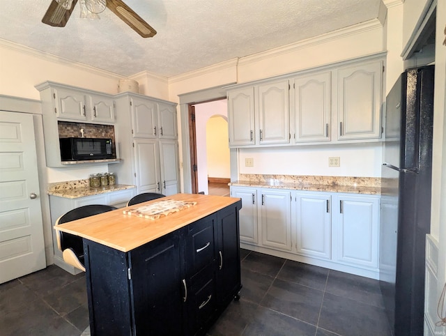 kitchen with a textured ceiling, a kitchen island, ornamental molding, and black appliances