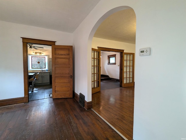 corridor with a textured ceiling, dark hardwood / wood-style floors, french doors, and sink