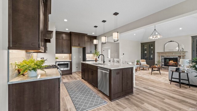 kitchen featuring light hardwood / wood-style flooring, a center island with sink, hanging light fixtures, and sink