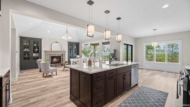 kitchen featuring pendant lighting, light stone counters, sink, a fireplace, and appliances with stainless steel finishes