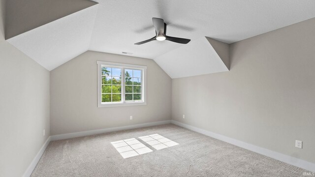 additional living space featuring light carpet, a textured ceiling, lofted ceiling, and ceiling fan