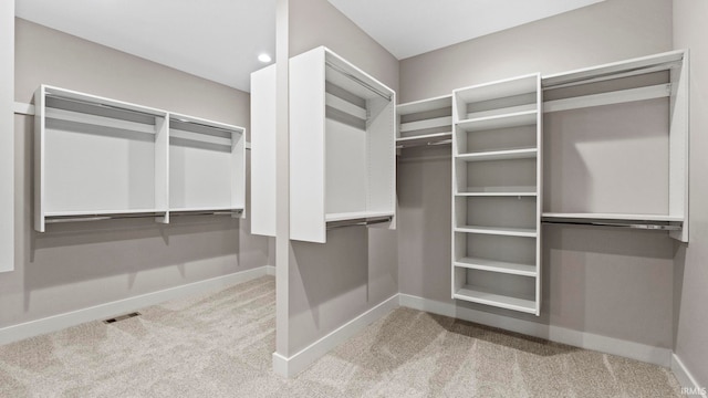 walk in closet featuring light colored carpet