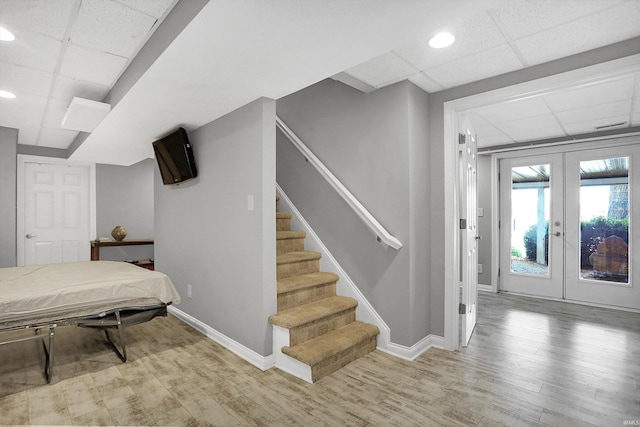 interior space featuring a drop ceiling, french doors, and hardwood / wood-style flooring