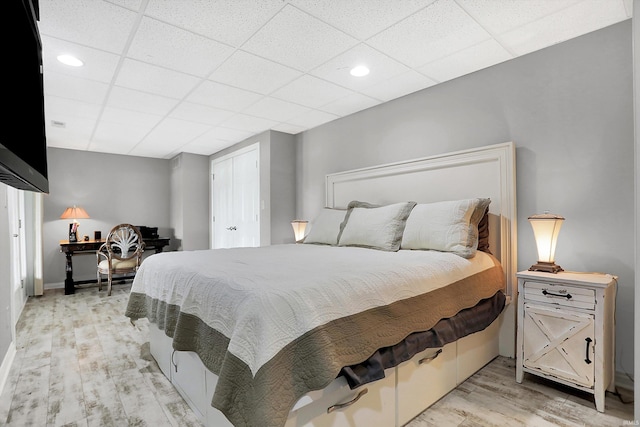 bedroom featuring a drop ceiling and light hardwood / wood-style floors