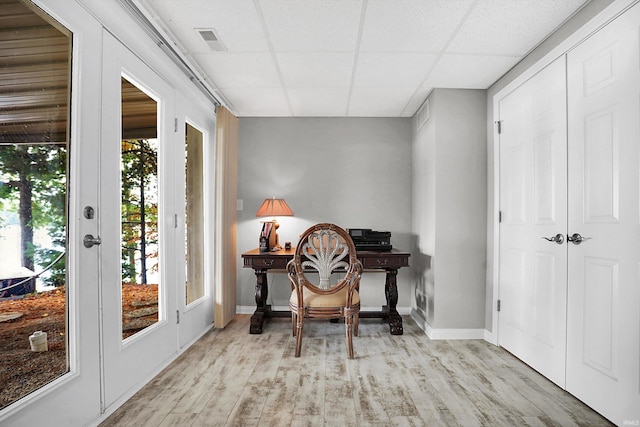 home office featuring light wood-type flooring and a paneled ceiling