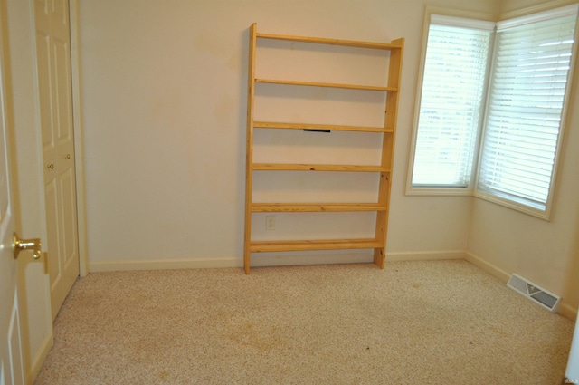 unfurnished bedroom featuring multiple windows, light colored carpet, and a closet