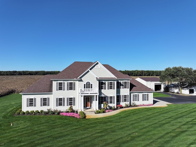 colonial inspired home featuring a balcony and a front yard