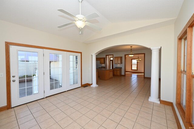 empty room with lofted ceiling, ceiling fan, light tile patterned floors, and ornate columns