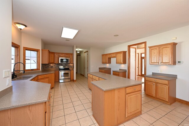 kitchen featuring a kitchen island, sink, light tile patterned floors, and stainless steel appliances