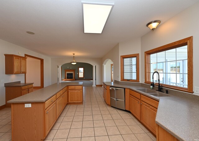 kitchen with dishwasher, light tile patterned floors, a center island, decorative light fixtures, and sink