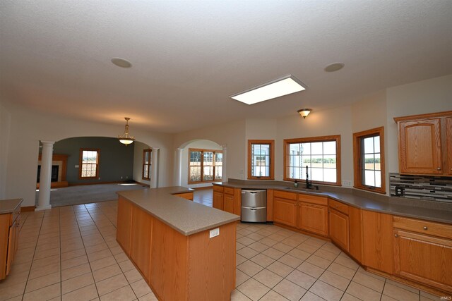 kitchen featuring ornate columns, a kitchen island, a healthy amount of sunlight, and sink