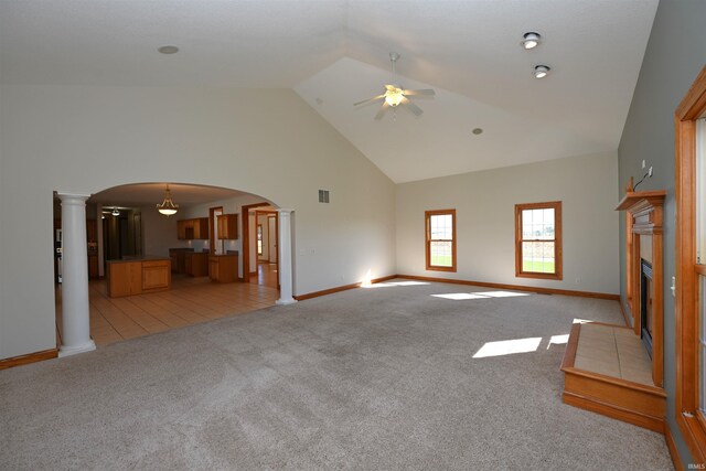 unfurnished living room with ceiling fan, light carpet, decorative columns, and high vaulted ceiling