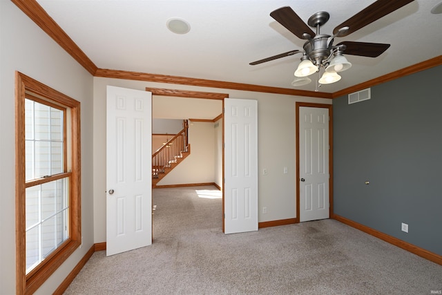 spare room with ceiling fan, light colored carpet, and crown molding