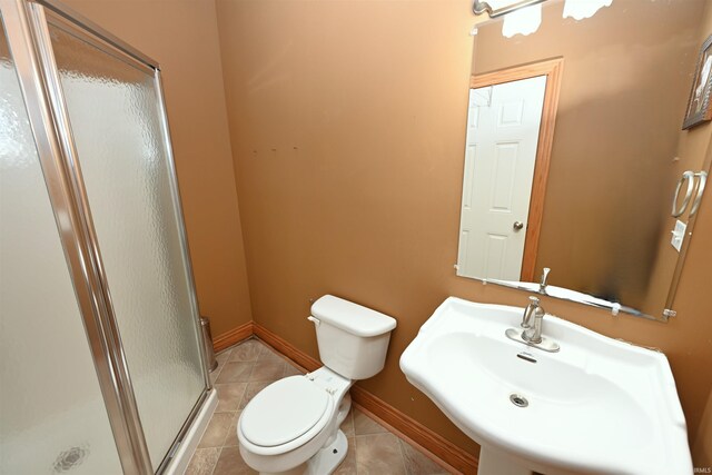 bathroom featuring sink, toilet, a shower with door, and tile patterned floors