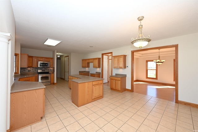 kitchen with hanging light fixtures, tasteful backsplash, stainless steel appliances, a center island, and a notable chandelier