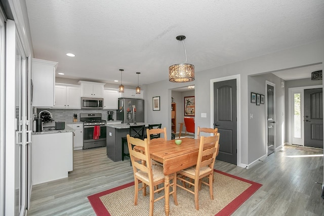 dining space featuring a textured ceiling, sink, and light hardwood / wood-style floors