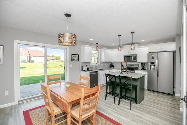 dining area with a textured ceiling, light hardwood / wood-style floors, and sink