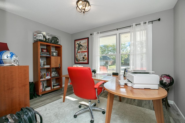 home office with a textured ceiling and light hardwood / wood-style floors