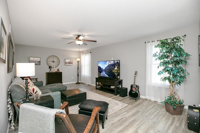 living room with light hardwood / wood-style flooring, ceiling fan, plenty of natural light, and a textured ceiling