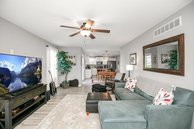 living room featuring light wood-type flooring, ceiling fan, and a wealth of natural light