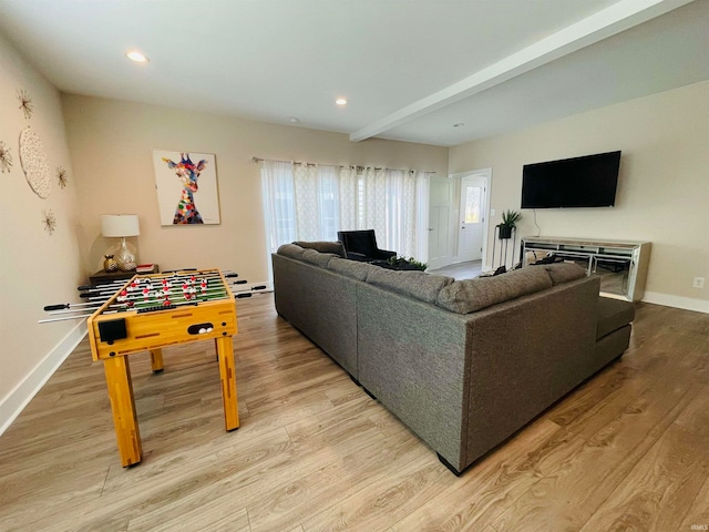 living room featuring beamed ceiling and light hardwood / wood-style floors