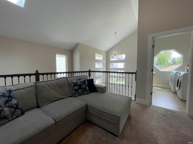 carpeted living room featuring a healthy amount of sunlight, washing machine and dryer, an inviting chandelier, and high vaulted ceiling