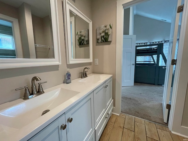 bathroom with wood-type flooring, vanity, and lofted ceiling